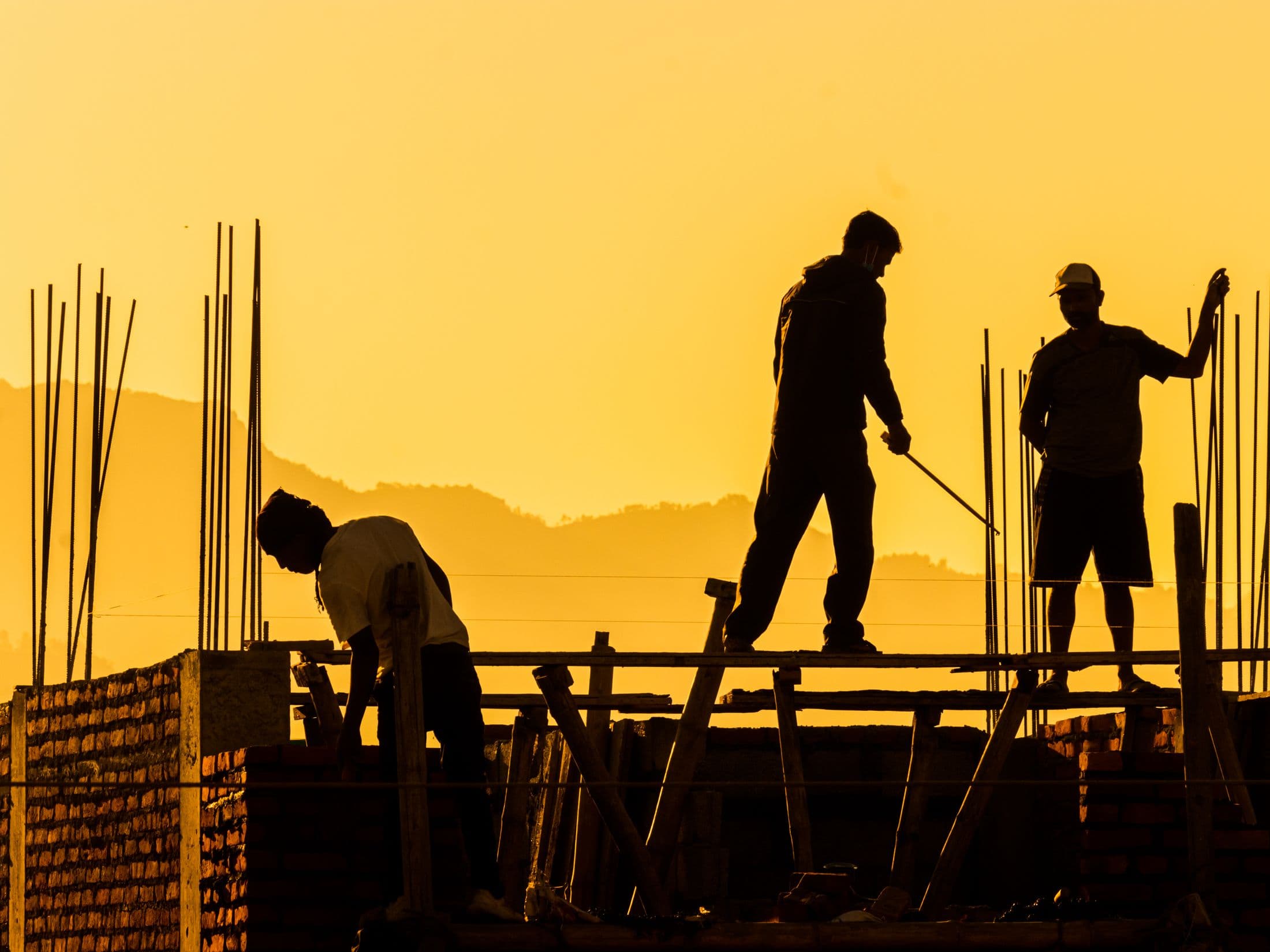 A construction crew silhouetted against a golden sunset